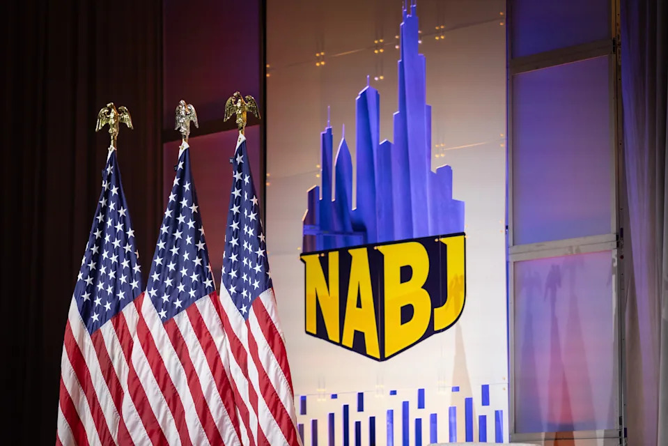 NABJ stage with U.S. flags and a city skyline backdrop at a formal event