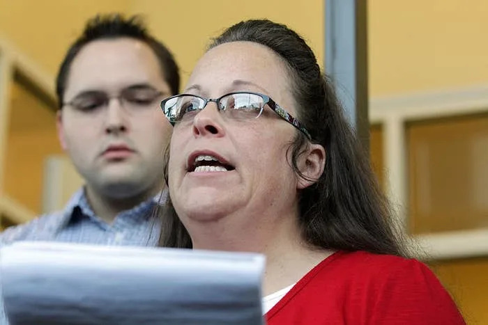 Two individuals at a press event, one holding a document