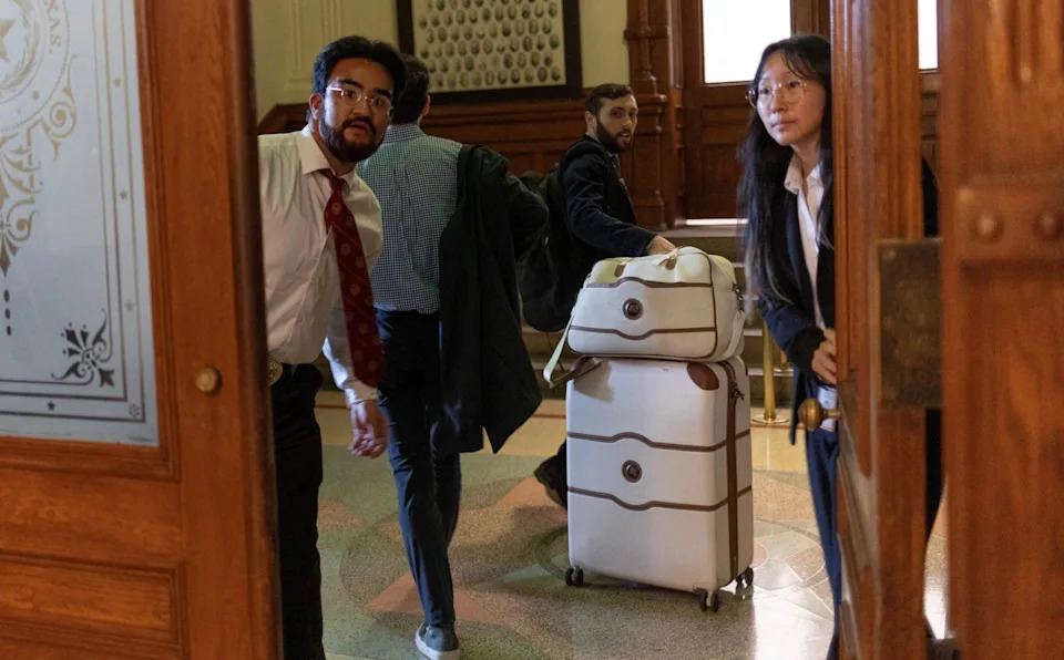 Andrew Lindinger, the chief legislative director for Nicole Collier, delivers Ms Collier's suitcase to the House chamber where she is choosing to remain