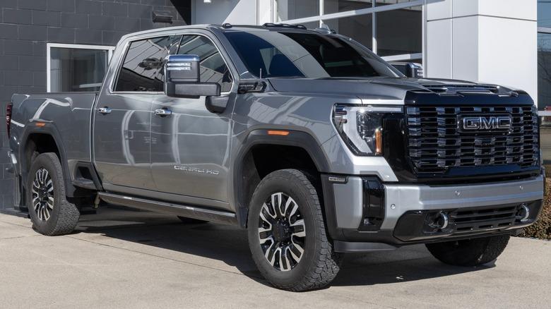 A gray GMS Sierra crew-cab pickup parked in front of a shop
