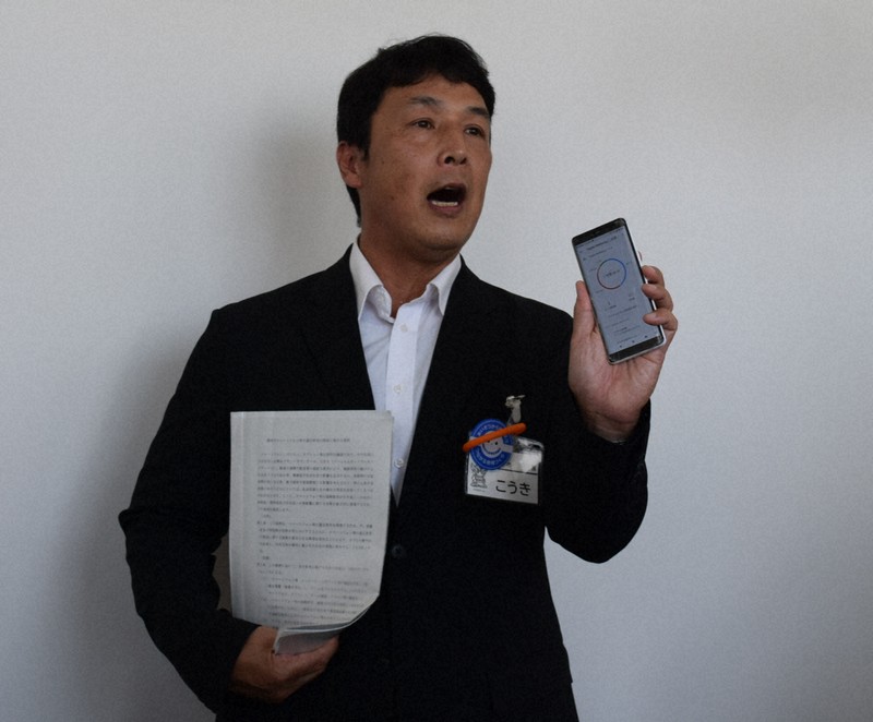 自身のスマホを手に条例案の趣旨について説明する愛知県豊明市の小浮正典市長＝市役所で2025年8月25日午前11時52分、式守克史撮影