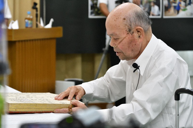 犠牲者346人の名前、続き柄、年齢を読み上げる元開拓団員の山下幸雄さん＝兵庫県豊岡市但東町で2025年8月17日午後2時10分、浜本年弘撮影