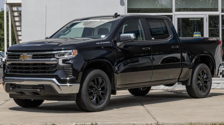 A black Chevrolet Silverado crew cab pickup parked in front of a dealership