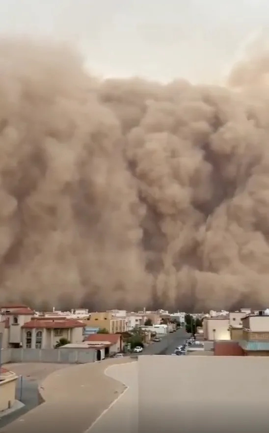 Massive sandstorm approaches a small town, engulfing buildings and streets, reducing visibility
