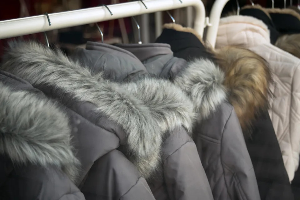 Winter coats with fur collars lined up on a rack