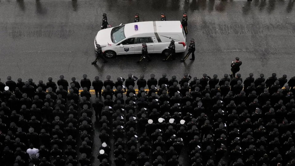 Officers flank each side of the white hearse carrying Islam's remains as it drives down White Plains Road after the funeral service on Thursday. - Yuki Iwamura/AP