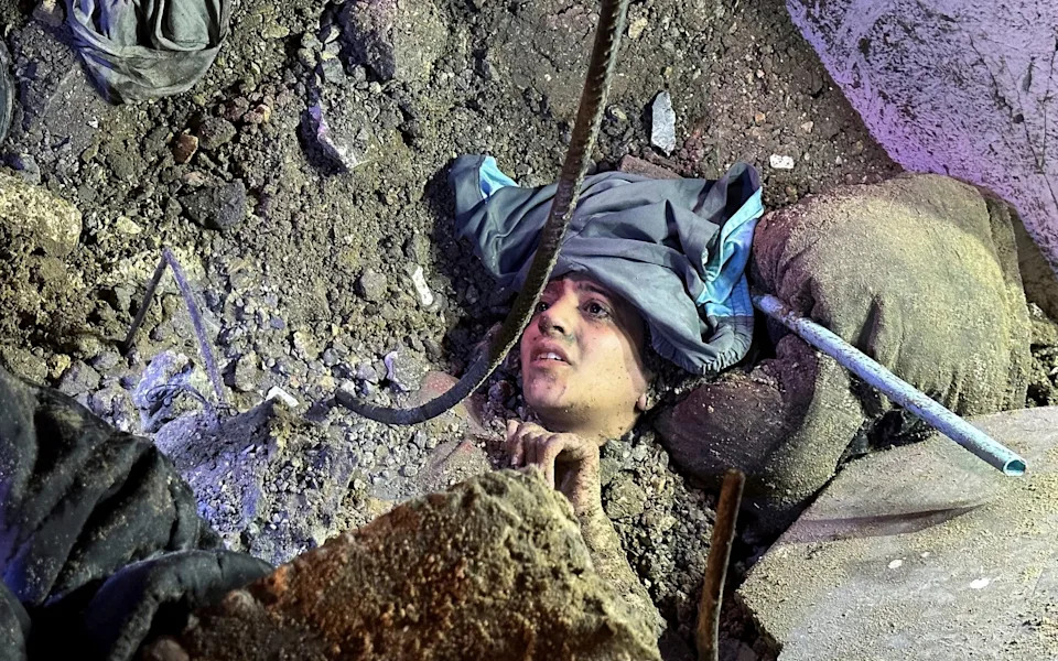 A Palestinian woman was trapped under the rubble of a house, which was hit in an Israeli strike. She was rescued after this picture was taken