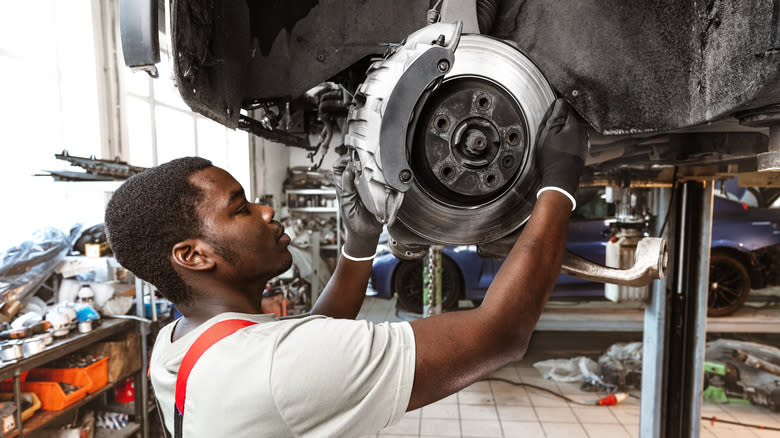 A mechanic replacing a car's brake pads.