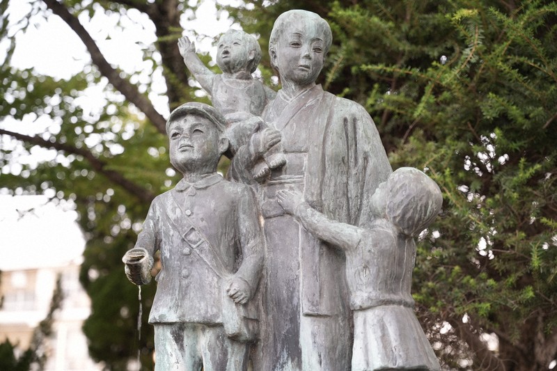 忠霊塔の隣に立っている母子像。男児が持つコップから水が滴っている＝奈良県三宅町で2025年8月15日午前5時49分、矢追健介撮影