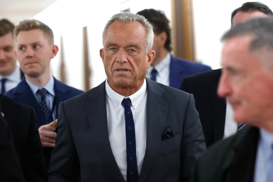 A man in a suit and tie walks with a group of people in formal attire