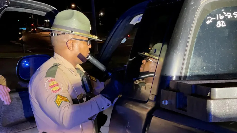 Sgt. Anthony Johnson uses a flashlight to search a pickup truck