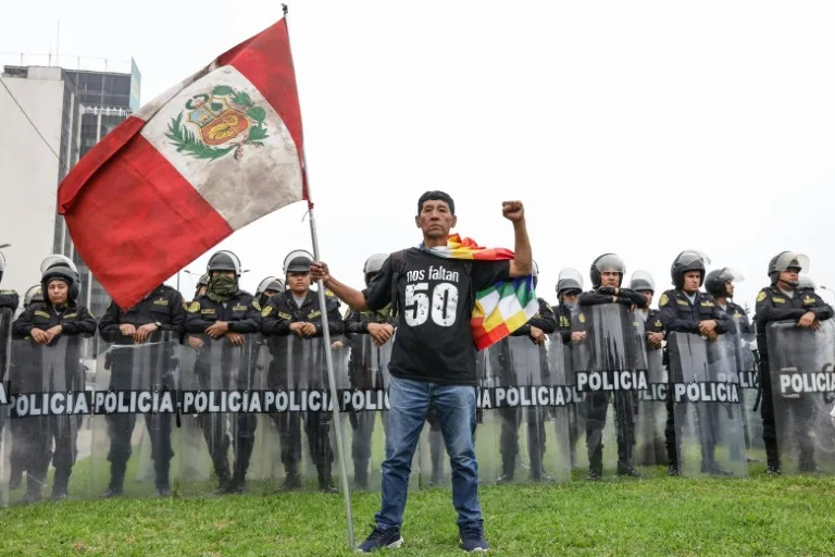A demonstrator holds a Peruvian flag and wears a shirt that reads "We are missing 50" in tribute to those killed during the 2022–2023 anti-government protests, during a 2025 march against the government of Peruvian President Dina Boluarte in Lima (CONNIE FRANCE)