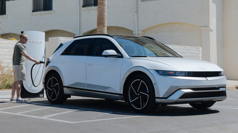 a man plugging a white Ioniq 5 into a Tesla charger