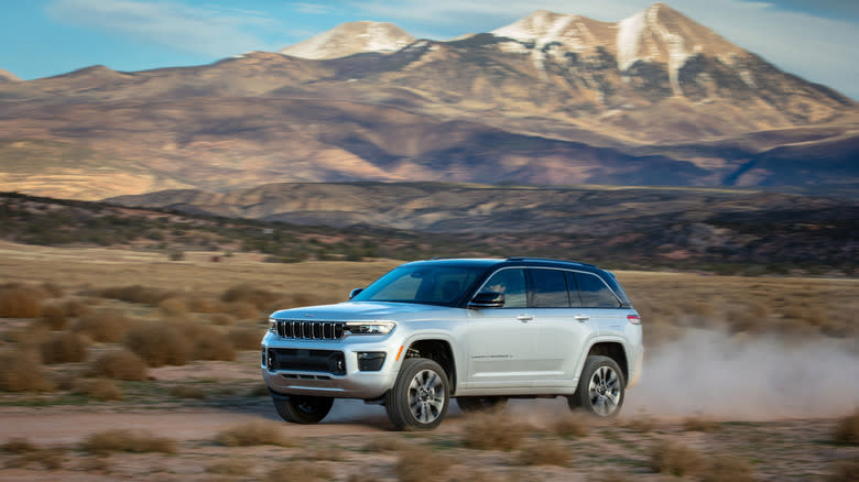 A silver Grand Cherokee driving on a dirt road in the desert