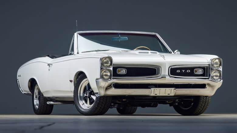 A white convertible 1966 Pontiac GTO parked against a gray background.