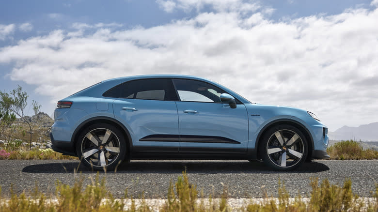 A blue Porsche Macan EV seen in a side-view
