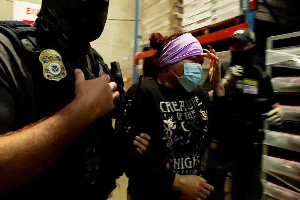 A woman is detained during a raid by Immigration and Customs Enforcement at a meat production plant in Omaha.
