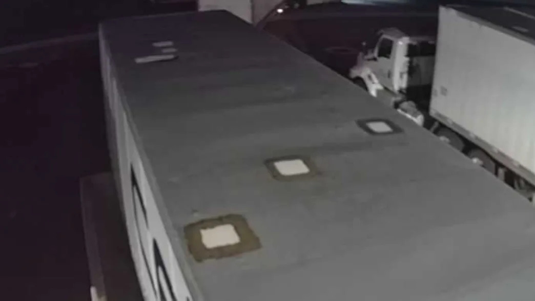 Black-and-white security photo of a truck trailer at night at a warehouse.