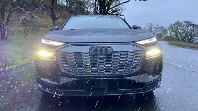 a head-on shot of a dark gray Audi SQ6 with its headlights on in the rain