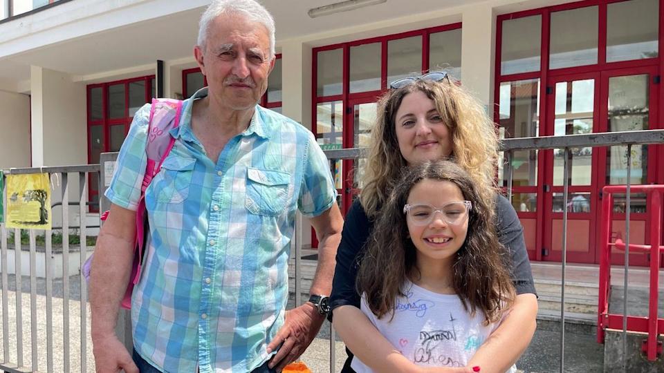 Un hombre mayor, una madre y su hija frente a un edificio
