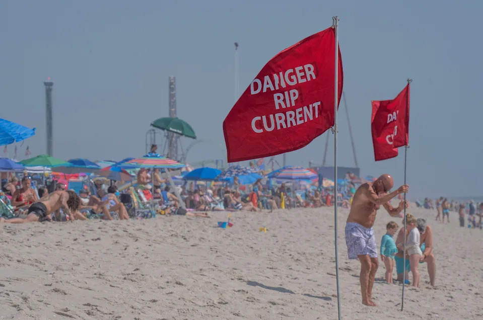 A man makes sure a rip current warning flag is firmly planted in the sand in Asbury Park Beach in New Jersey.