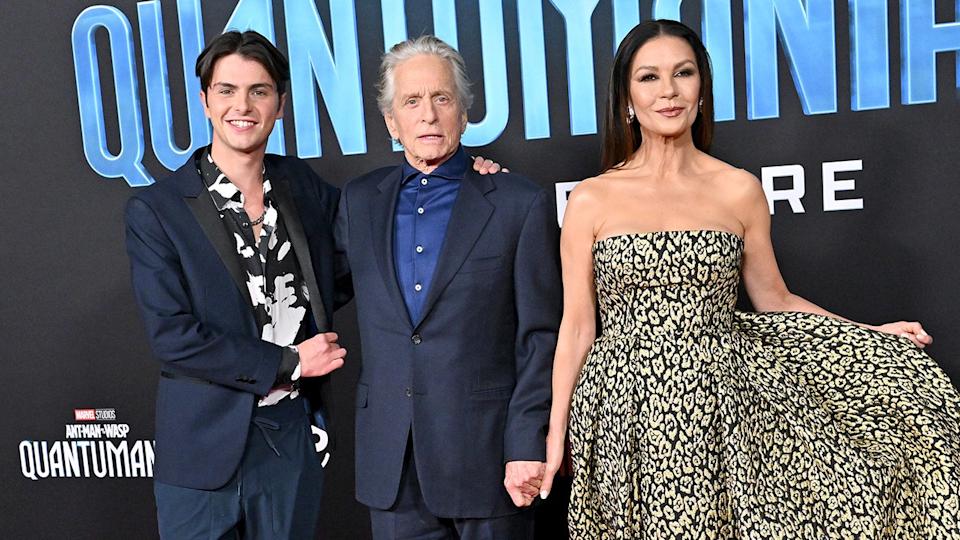 Michael Douglas con traje azul marino y camisa azul abotonada posa con su hijo Dylan también de traje y su mujer Catherine Zeta-Jones con un vestido estampado de leopardo en la alfombra