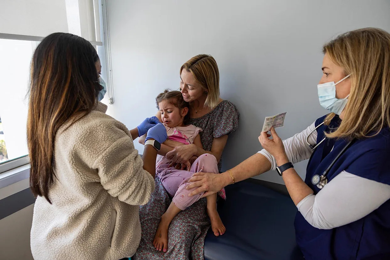 Dr. Neville Anderson, right, tries to cheer up and distract a young patient receiving her DTap Polio and MMR Chickenpox vaccinations in Los Angeles on March 25, 2025. (Allen J. Schaben / Los Angeles Times via Getty Images file)