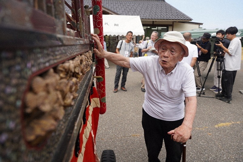 氏子総代長を約20年務めていたという小松与一さんも神輿復興祭に駆けつけた。みこしを触って元通りの姿を喜んでいた＝石川県輪島市で2025年7月31日午前10時57分、岩本一希撮影