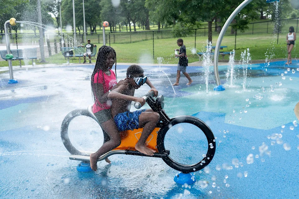 Siblings Shyer Jones, 11, and Ameer Jones, 12, pretend to drive the water motorcycle on the splash pad at Washington Park in Milwaukee on the afternoon of July 23, 2025.