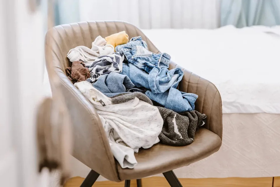 Pile of unfolded dirty clothes on a chair.