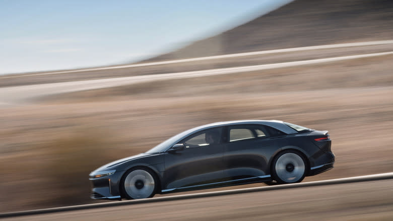 A Lucid Air sedan driving on a road in side view