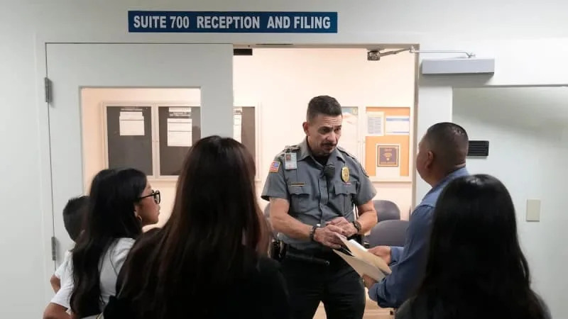 An officer listens to a question as he directs people to a courtroom, Wednesday, Jan. 10, 2024, in an immigration court in Miami. Immigration courts are buckling under an unprecedented 3 million pending cases. &#xa9;Wilfredo Lee