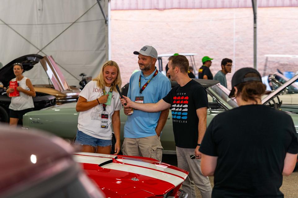 Attendees exploring classic cars at Mecum auction event.