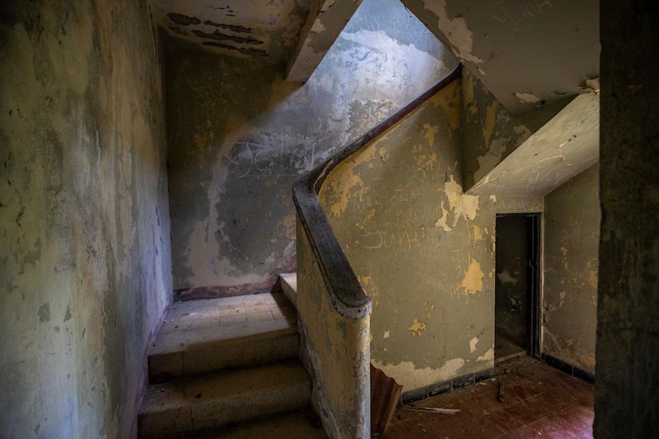 Parte del interior de la Casa de Caoba. Se ve una escalera despintada, paredes con escritos y suciedad.