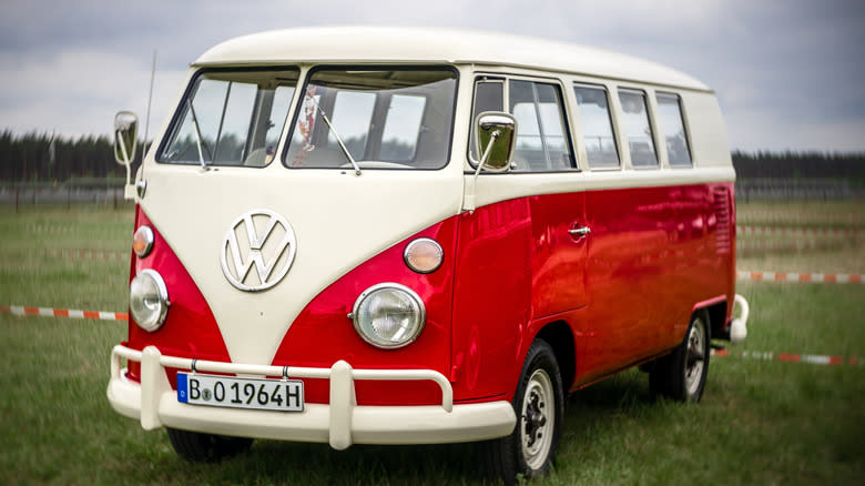 A red and white 1964 Volkswagen Microbus on the grass.