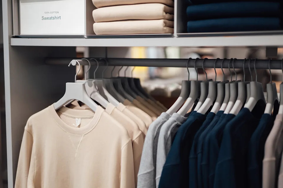 Sweatshirts neatly hung and stacked on shelves in a clothing store