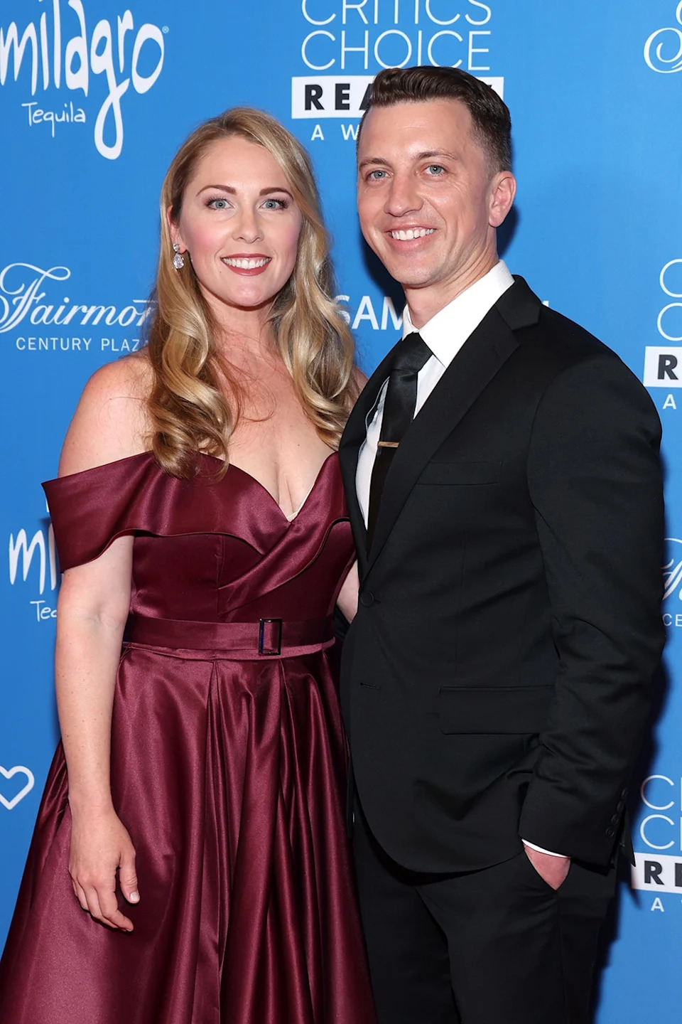 Denise Huskins wearing a burgundy gown posing with Aaron Quinn in a black suit and tie.