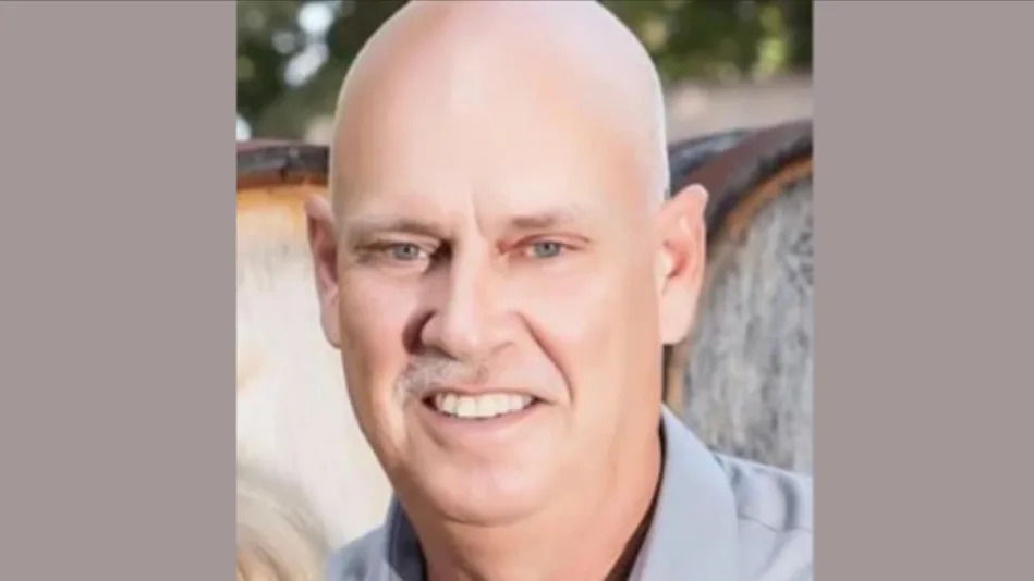 Close-up of a bald man smiling, wearing a collared shirt