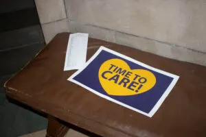 People attending a Capitol Rotunda rally left a sign on a bench in the statehouse saying, “Time to Care!” Mar. 6, 2025 (Juan Salinas II/Nebraska Examiner)
