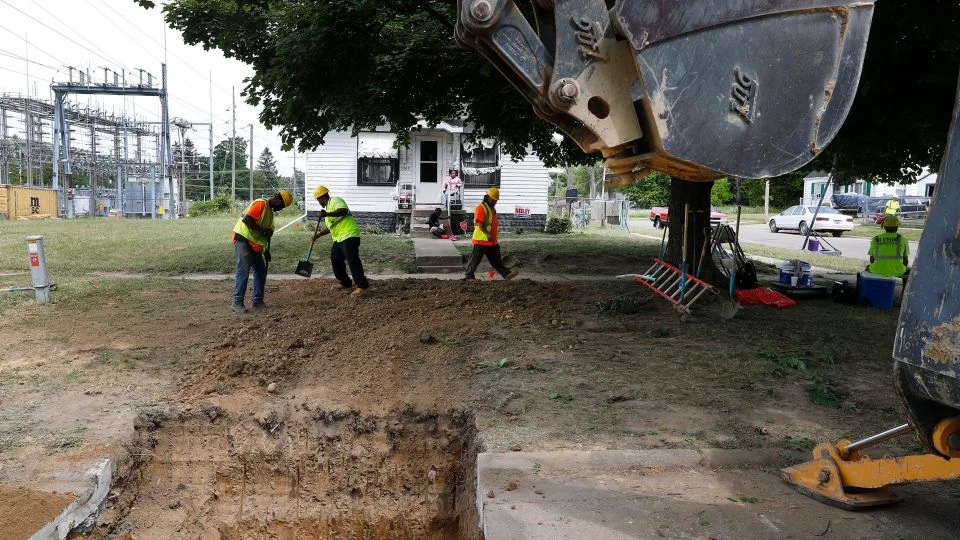 Workers backfill a hole used to replace a lead pipe with copper water supply lines to a home in Flint, Michigan, on July 20, 2018. - Paul Sancya/AP