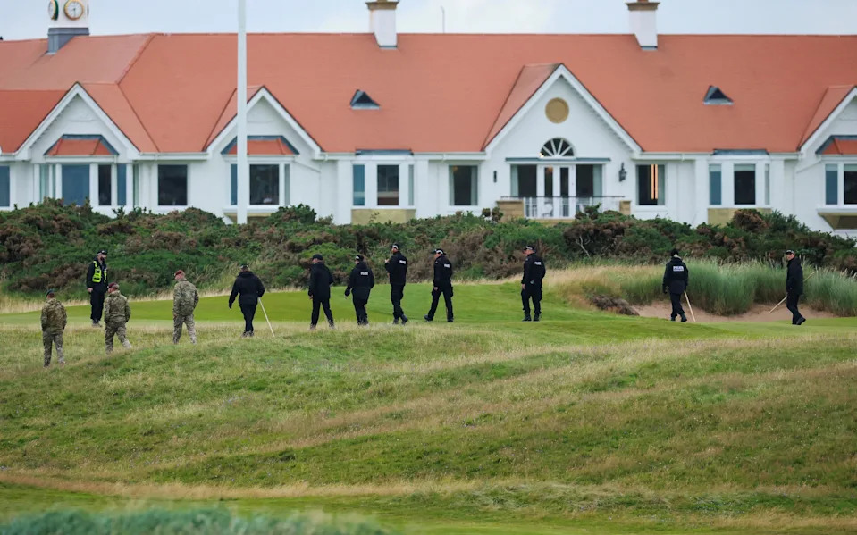 A line of military personnel and police sweep a stretch of grass outside the luxury Turnberry resort