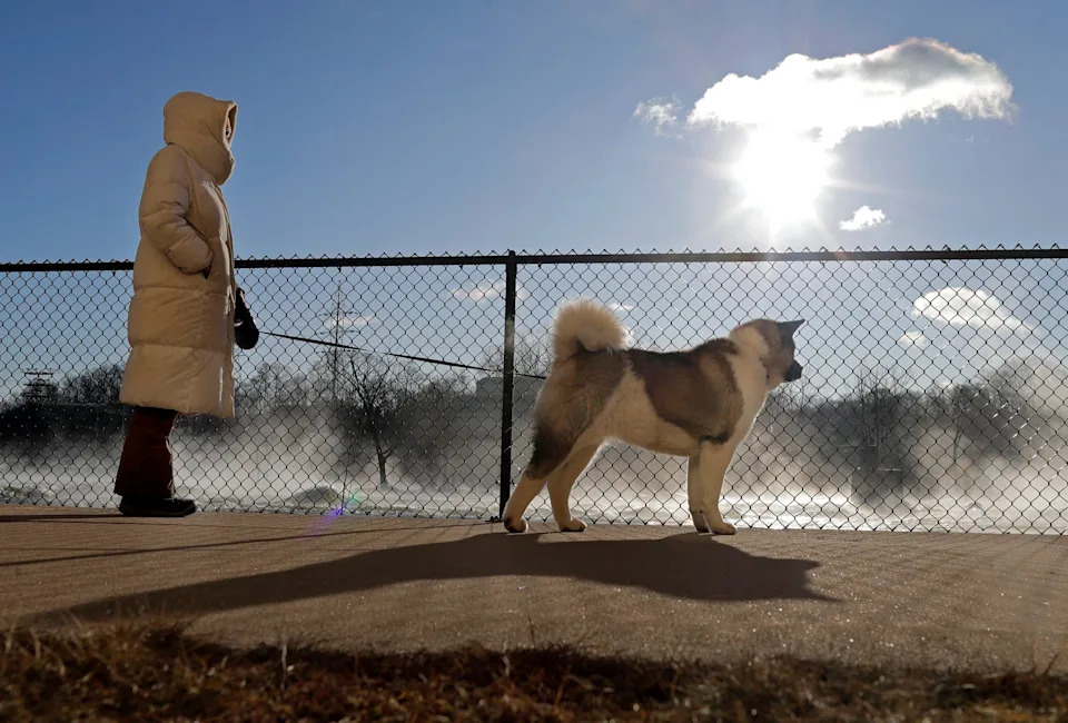 Frigid temperatures and wind chills below zero greet Kim Massey and her dog Beau as they take a walk along the Fox River, near Atlas Mill in Appleton, Wisconsin on January 20, 2025.