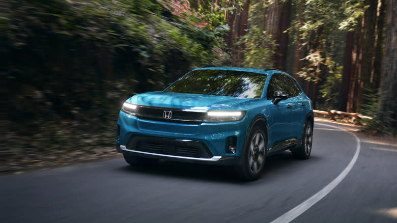 a blue Prologue driving around a corner in the forest