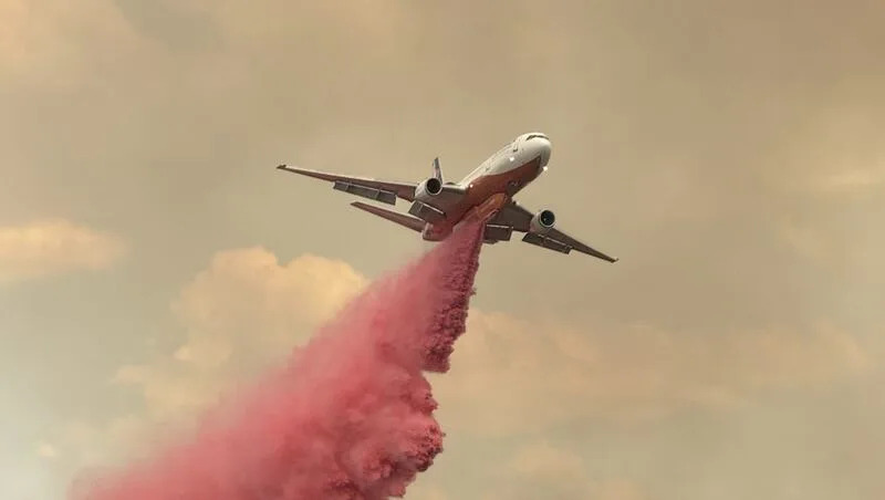 A plane drops fire retardant on the Monroe Canyon Fire in the Bear Valley area of Sevier County on Wednesday. Crews said Friday the fire crossed Bear Valley Road, but they&#39;ve been able to prevent it from crossing state Route 24, so far. 