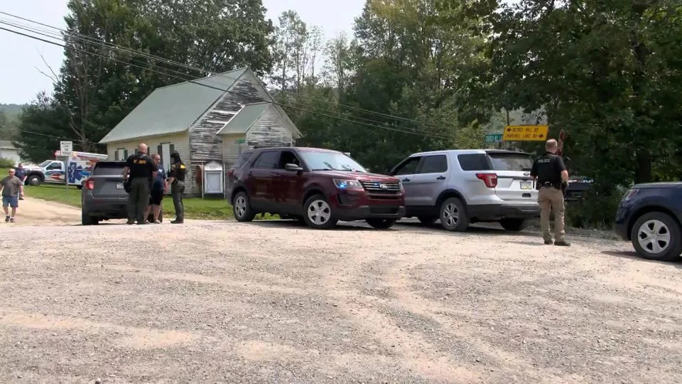 Police officers block the street leading to where two Pennsylvania state troopers were shot Thursday, near Thompson Township in Susquehanna County, Pennsylvania. - WBNG-TV
