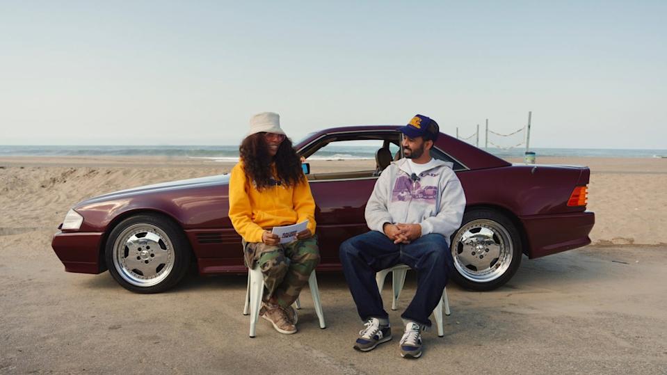 two people sit by a mercedes