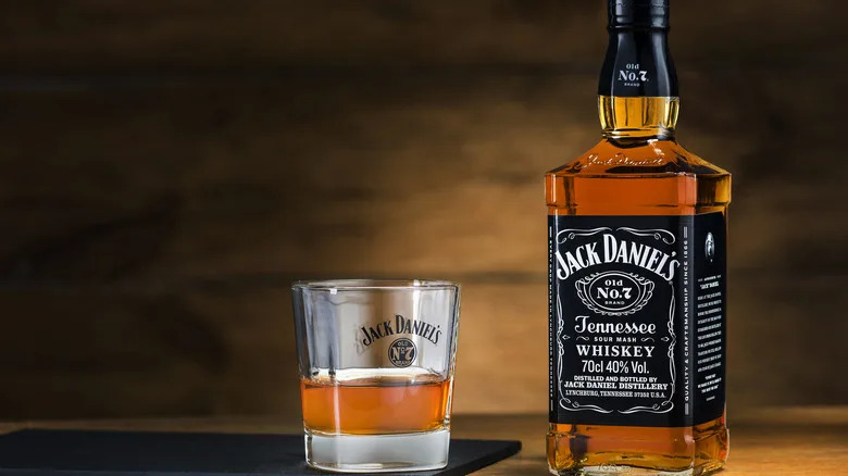A bottle of Jack Daniels Tennessee Whiskey next to a small glass of Jack Daniels