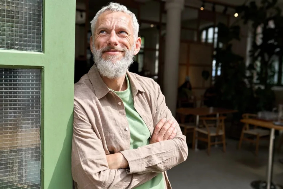 Older man smiling standing outside.