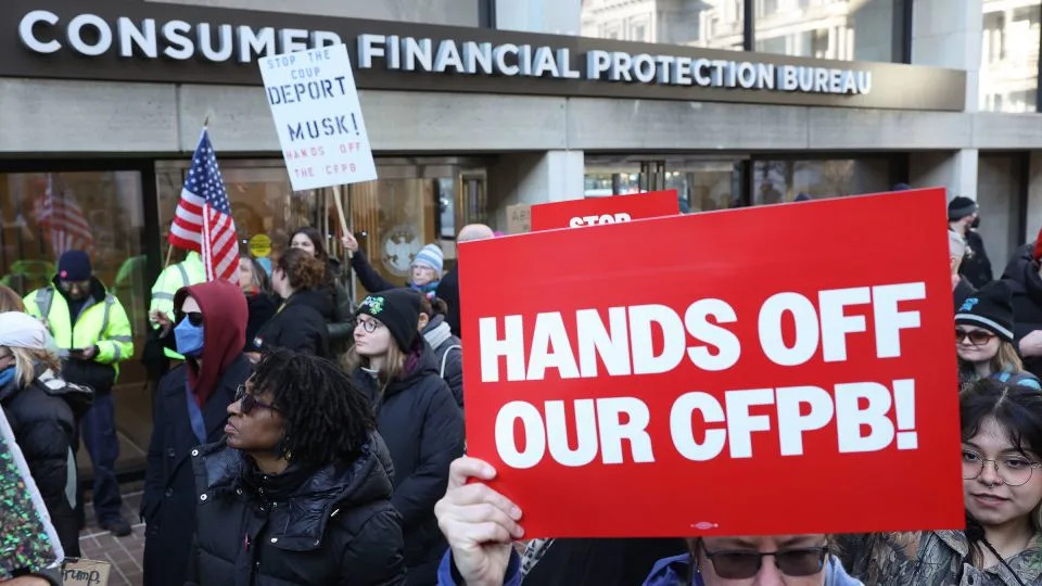 Demonstrators raise signs and posters during a rally outside the Consumer Financial Protection Bureau headquarters in Washington, DC, on February 10, 2025. - Jemal Countess/Getty Images for MoveOn/File