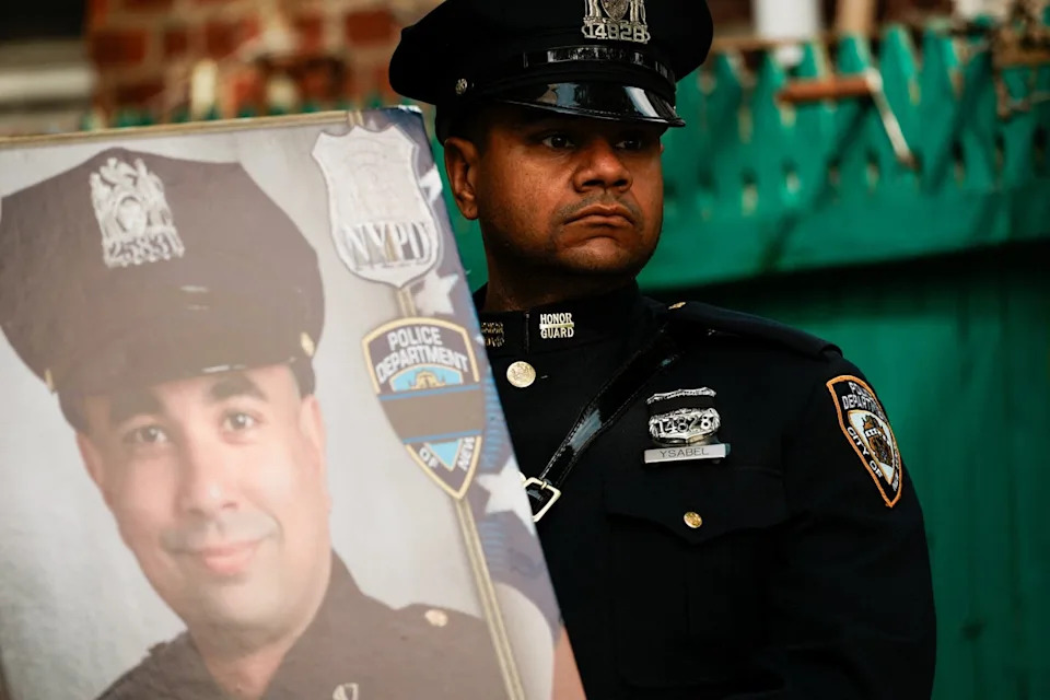 A police officer stands next to a picture of  Islam on the day of his funeral (REUTERS)